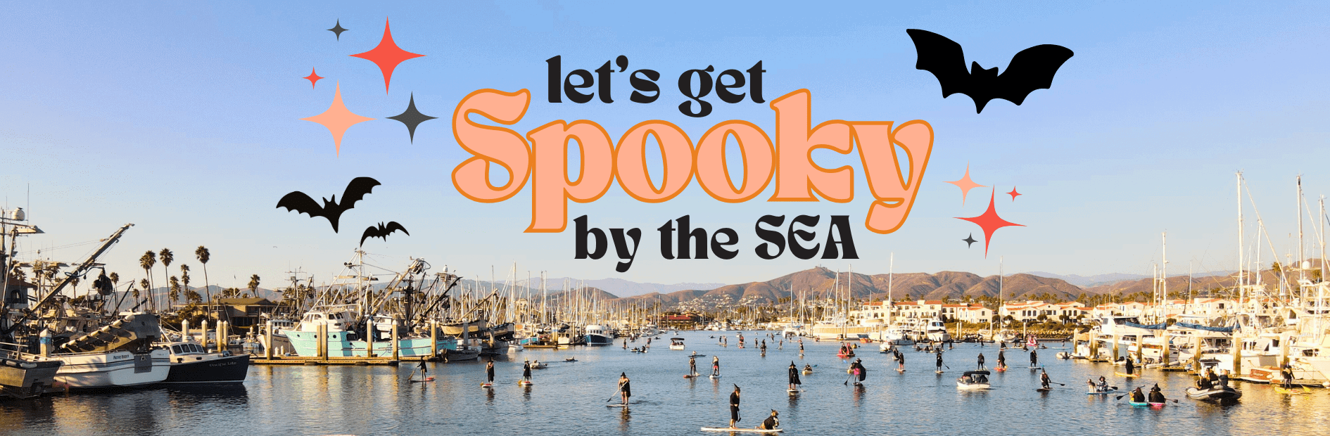 People paddleboarding in a marina under a clear blue sky with Halloween-themed text and decorations.