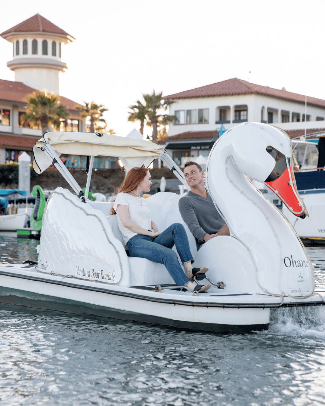 Couple enjoying a boat ride on a swan-shaped pedal boat at Ventura Harbor Village.