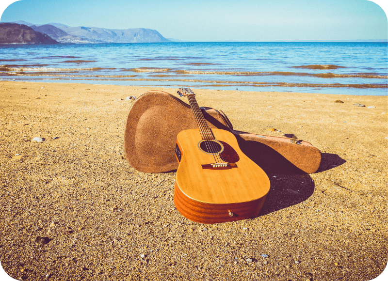 Acoustic guitar on Ventura Beach with ocean and mountains in background.