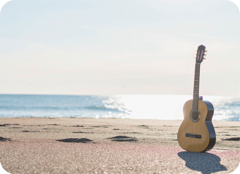 Acoustic guitar on Ventura Harbor Beach during sunset for live music event.