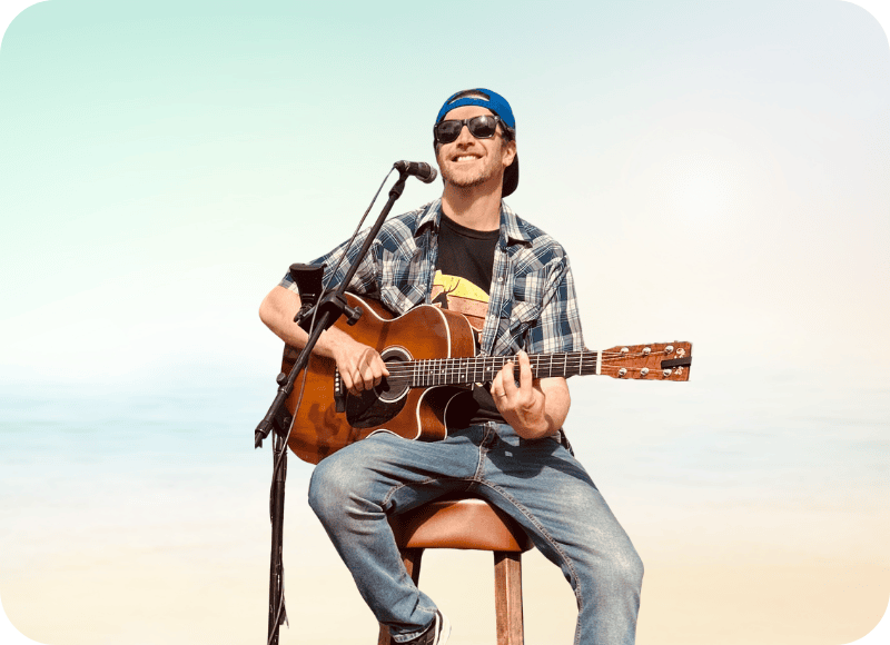 Musician playing guitar and singing at Ventura Harbor Village during live music event.