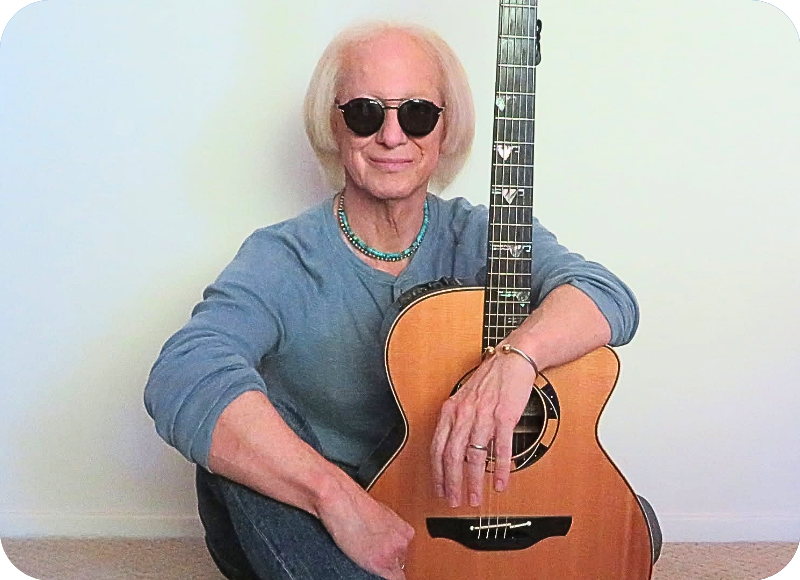 Musician with sunglasses holding an acoustic guitar at Ventura Harbor Village.