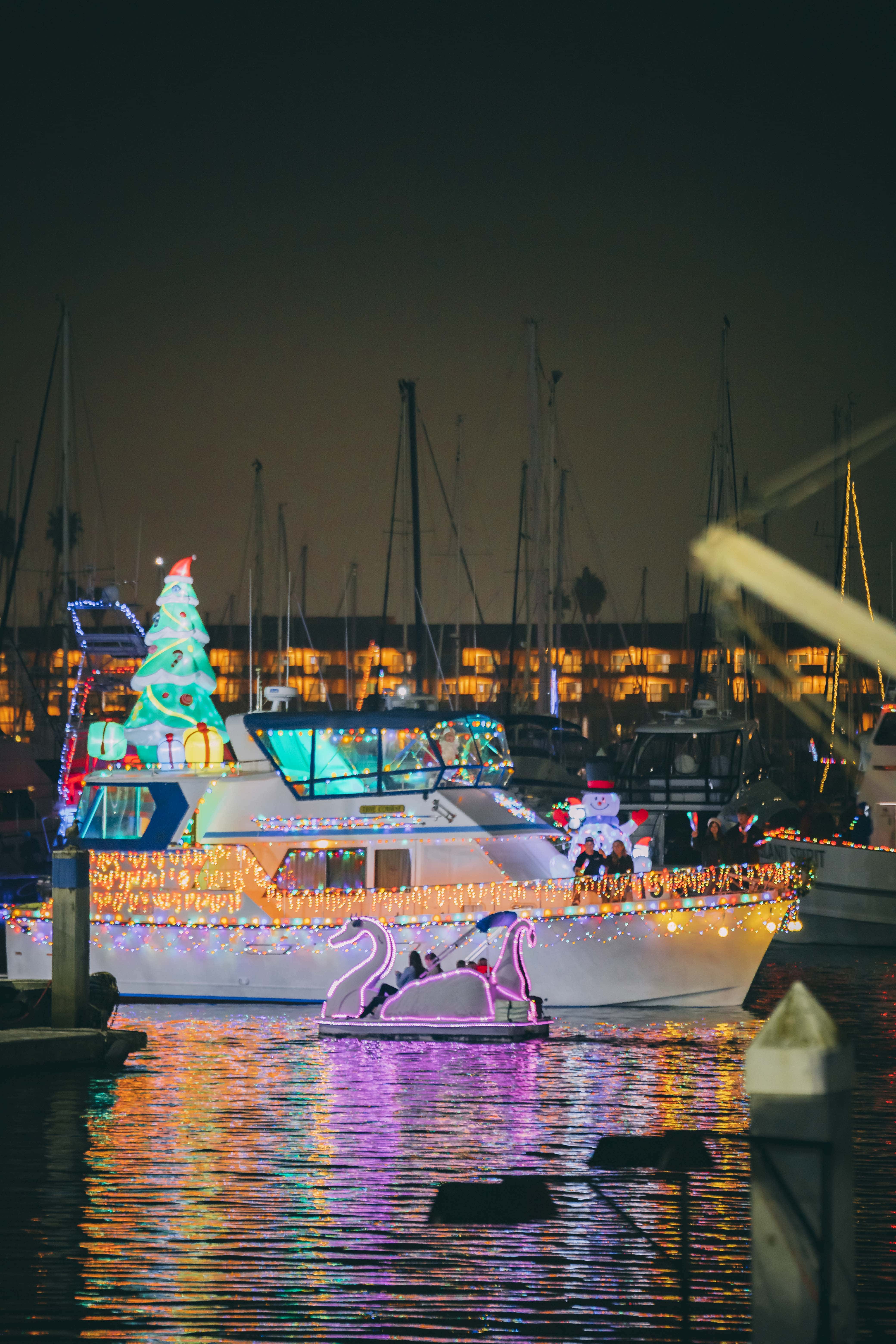 Festively decorated boat with Christmas lights and swan figures at Ventura Harbor.