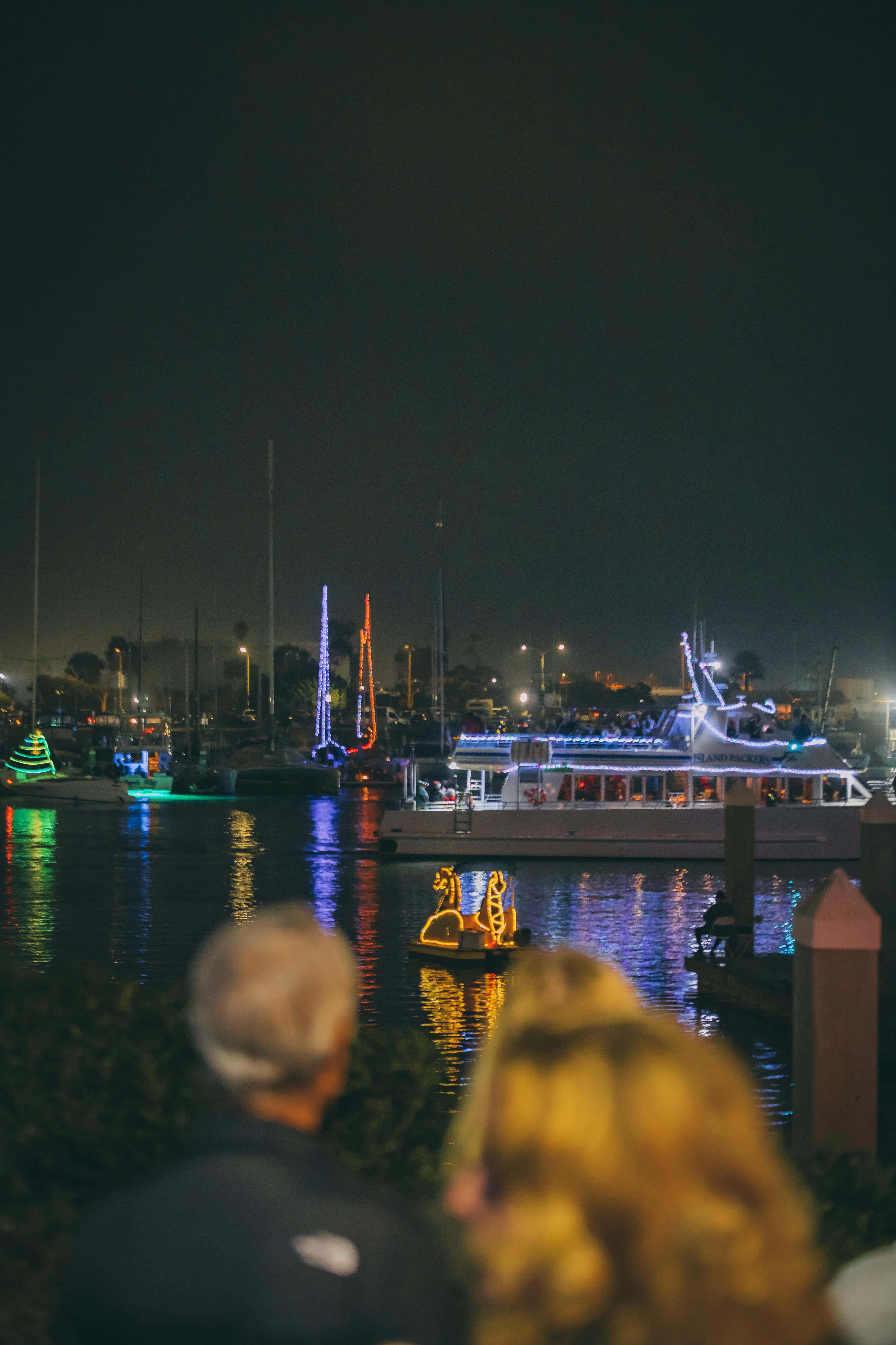 Night view of Ventura Harbor with illuminated boats and reflections on water.